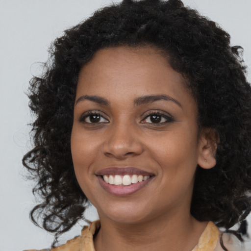 Joyful black young-adult female with long  brown hair and brown eyes
