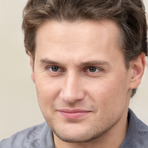 Joyful white young-adult male with short  brown hair and grey eyes