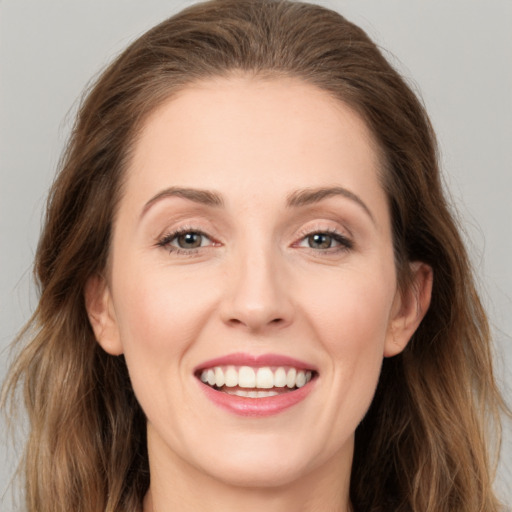 Joyful white young-adult female with long  brown hair and grey eyes