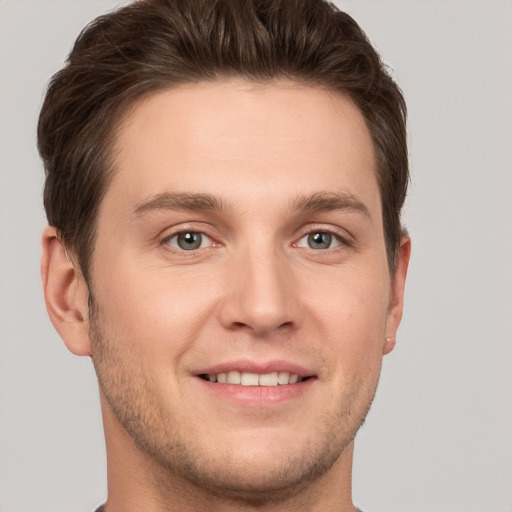 Joyful white young-adult male with short  brown hair and grey eyes