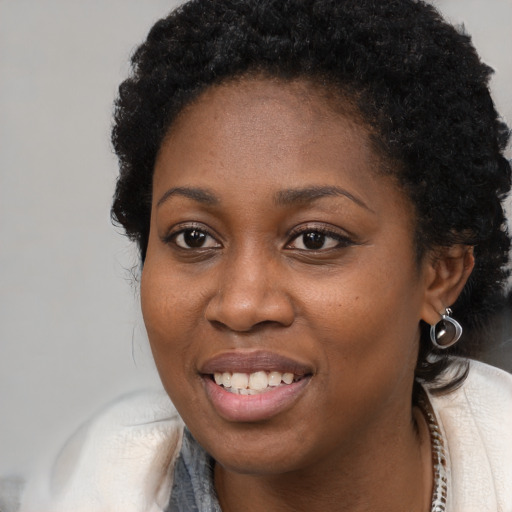 Joyful black young-adult female with long  brown hair and brown eyes