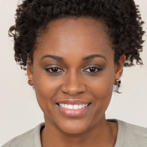 Joyful black young-adult female with short  brown hair and brown eyes