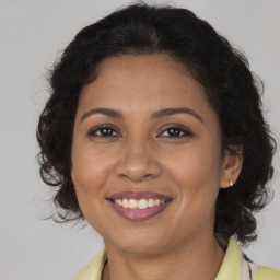 Joyful latino adult female with medium  brown hair and brown eyes