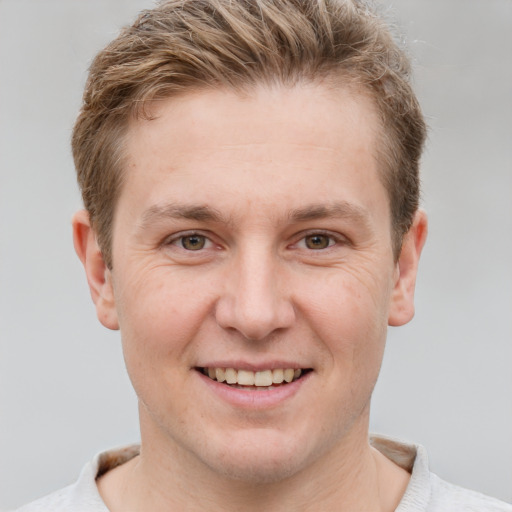 Joyful white young-adult male with short  brown hair and grey eyes