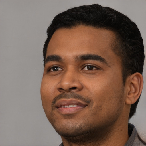 Joyful black young-adult male with short  black hair and brown eyes