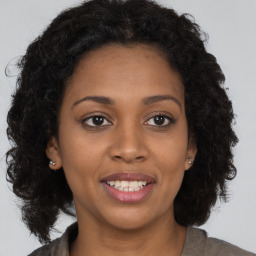 Joyful black young-adult female with long  brown hair and brown eyes