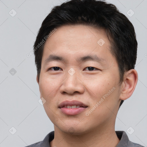 Joyful asian young-adult male with short  black hair and brown eyes