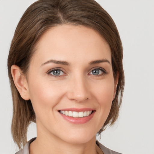 Joyful white young-adult female with medium  brown hair and grey eyes