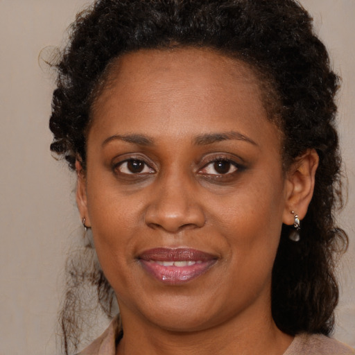 Joyful black adult female with long  brown hair and brown eyes