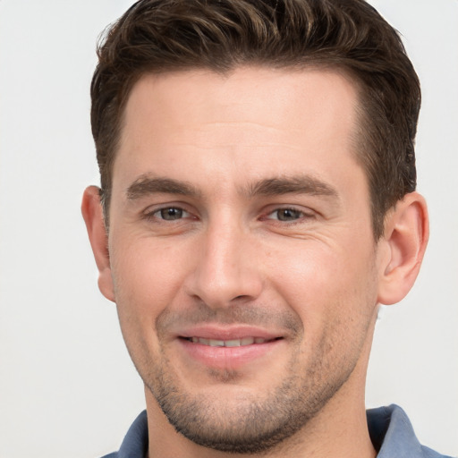 Joyful white young-adult male with short  brown hair and grey eyes