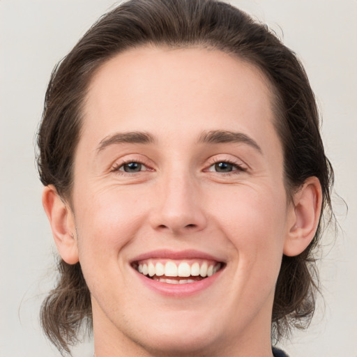 Joyful white young-adult female with medium  brown hair and grey eyes