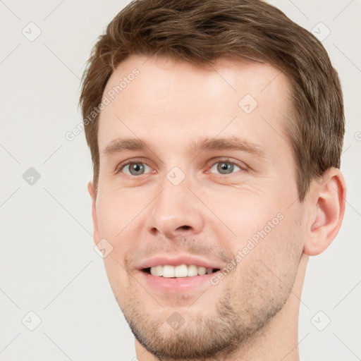 Joyful white young-adult male with short  brown hair and grey eyes