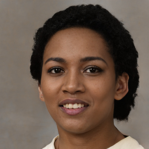 Joyful black young-adult female with short  black hair and brown eyes
