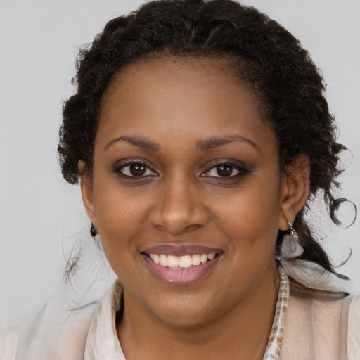 Joyful black young-adult female with long  brown hair and brown eyes