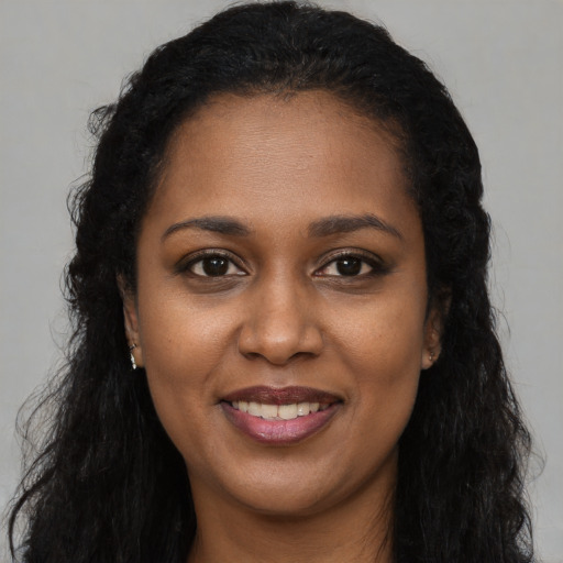 Joyful black young-adult female with long  brown hair and brown eyes