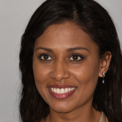 Joyful black young-adult female with long  brown hair and brown eyes