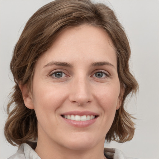 Joyful white young-adult female with medium  brown hair and grey eyes