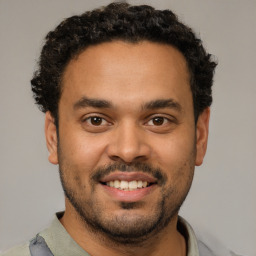 Joyful latino young-adult male with short  brown hair and brown eyes