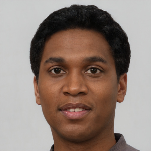 Joyful black young-adult male with short  black hair and brown eyes