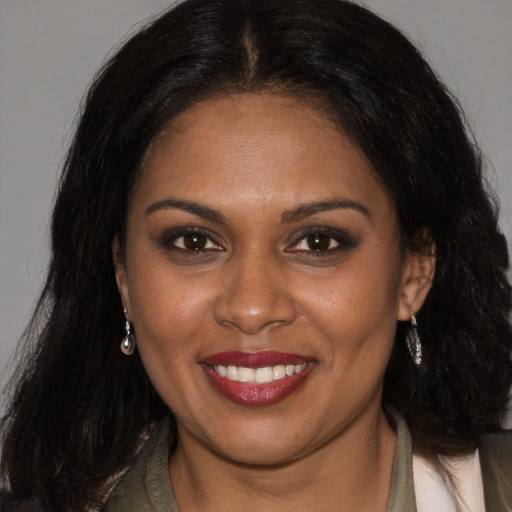 Joyful black young-adult female with long  brown hair and brown eyes
