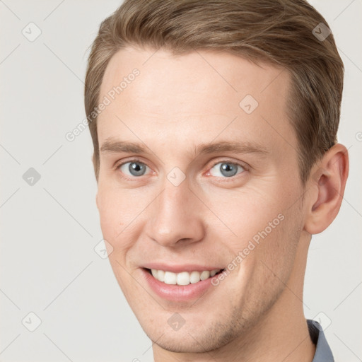 Joyful white young-adult male with short  brown hair and grey eyes