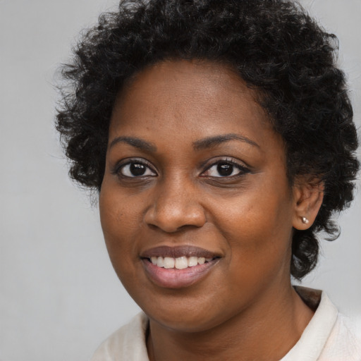 Joyful black young-adult female with long  brown hair and brown eyes