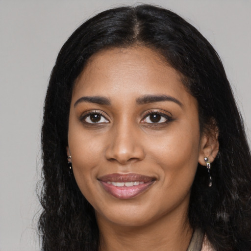 Joyful black young-adult female with long  black hair and brown eyes