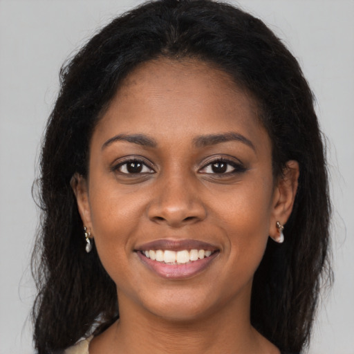 Joyful black young-adult female with long  brown hair and brown eyes