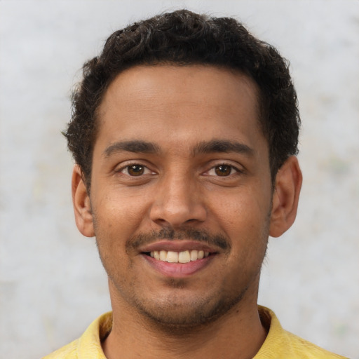 Joyful latino young-adult male with short  brown hair and brown eyes
