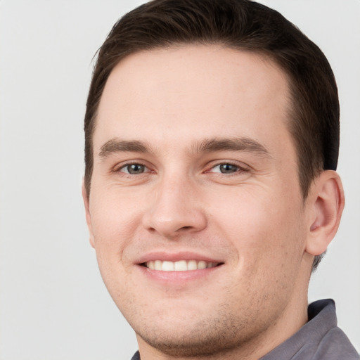 Joyful white young-adult male with short  brown hair and grey eyes