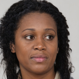 Joyful black young-adult female with long  brown hair and brown eyes