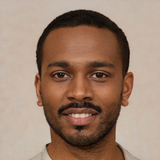 Joyful black young-adult male with short  black hair and brown eyes