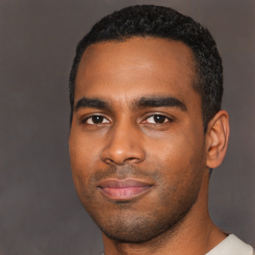 Joyful black young-adult male with short  black hair and brown eyes