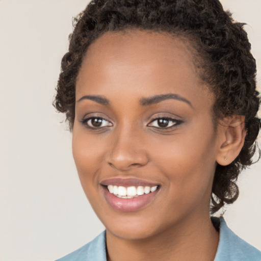 Joyful black young-adult female with long  brown hair and brown eyes