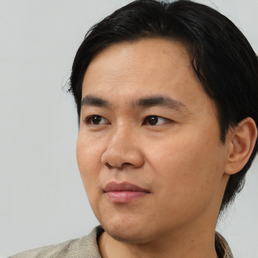 Joyful asian young-adult male with medium  black hair and brown eyes