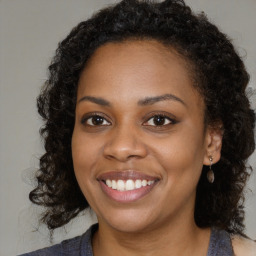 Joyful black young-adult female with long  brown hair and brown eyes