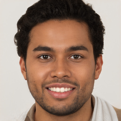 Joyful black young-adult male with short  brown hair and brown eyes