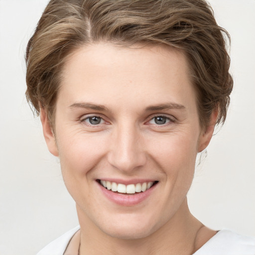 Joyful white young-adult female with short  brown hair and grey eyes