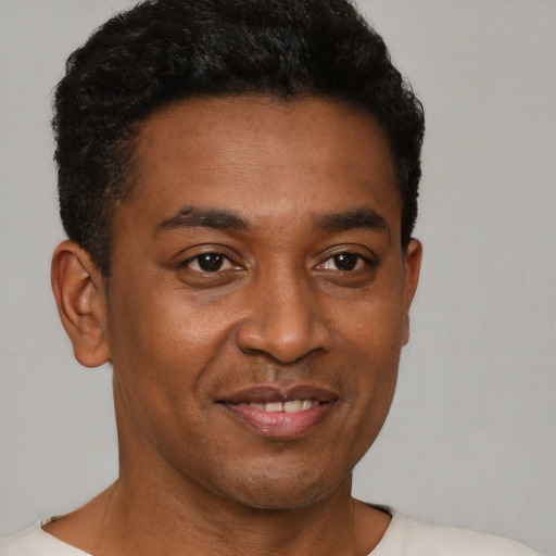 Joyful black young-adult male with short  brown hair and brown eyes