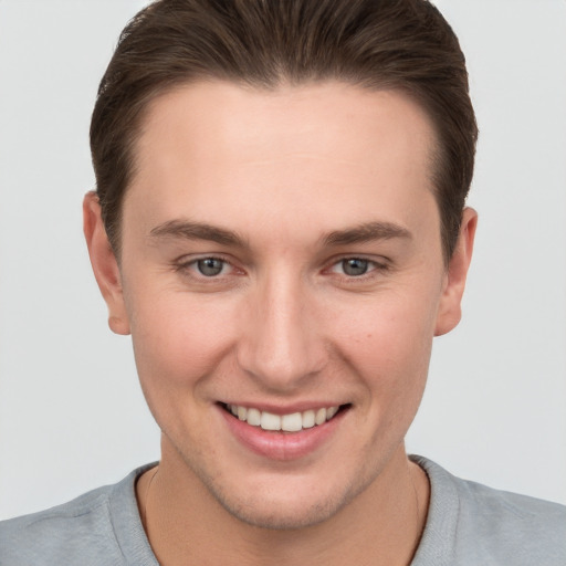 Joyful white young-adult male with short  brown hair and grey eyes