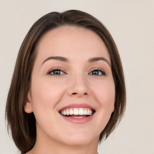 Joyful white young-adult female with medium  brown hair and green eyes