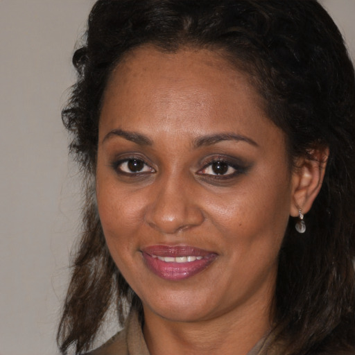 Joyful black young-adult female with long  brown hair and brown eyes