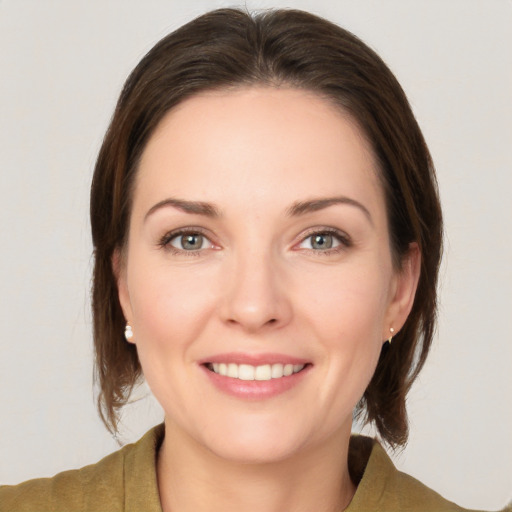 Joyful white young-adult female with medium  brown hair and grey eyes