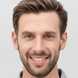 Joyful white young-adult male with short  brown hair and grey eyes