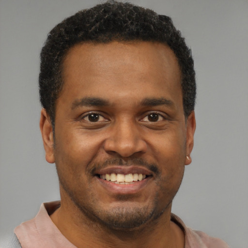 Joyful black young-adult male with short  brown hair and brown eyes
