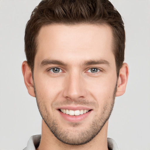 Joyful white young-adult male with short  brown hair and grey eyes