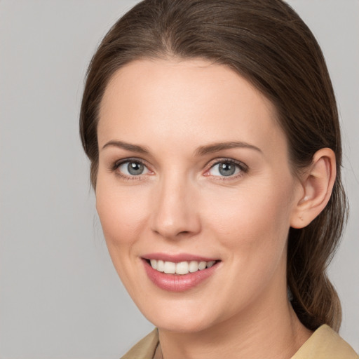 Joyful white young-adult female with medium  brown hair and grey eyes