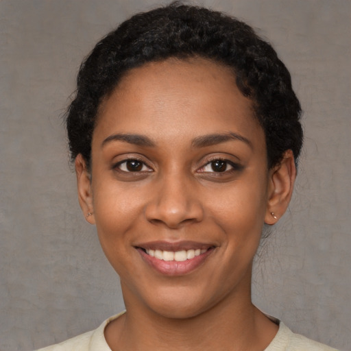 Joyful black young-adult female with short  black hair and brown eyes