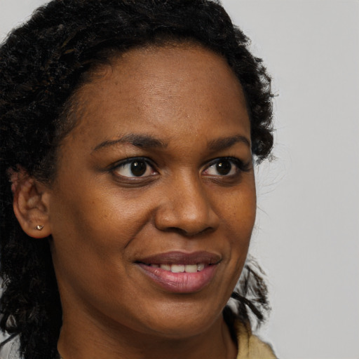 Joyful black young-adult female with long  brown hair and brown eyes