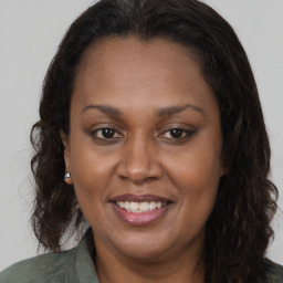 Joyful black adult female with long  brown hair and brown eyes